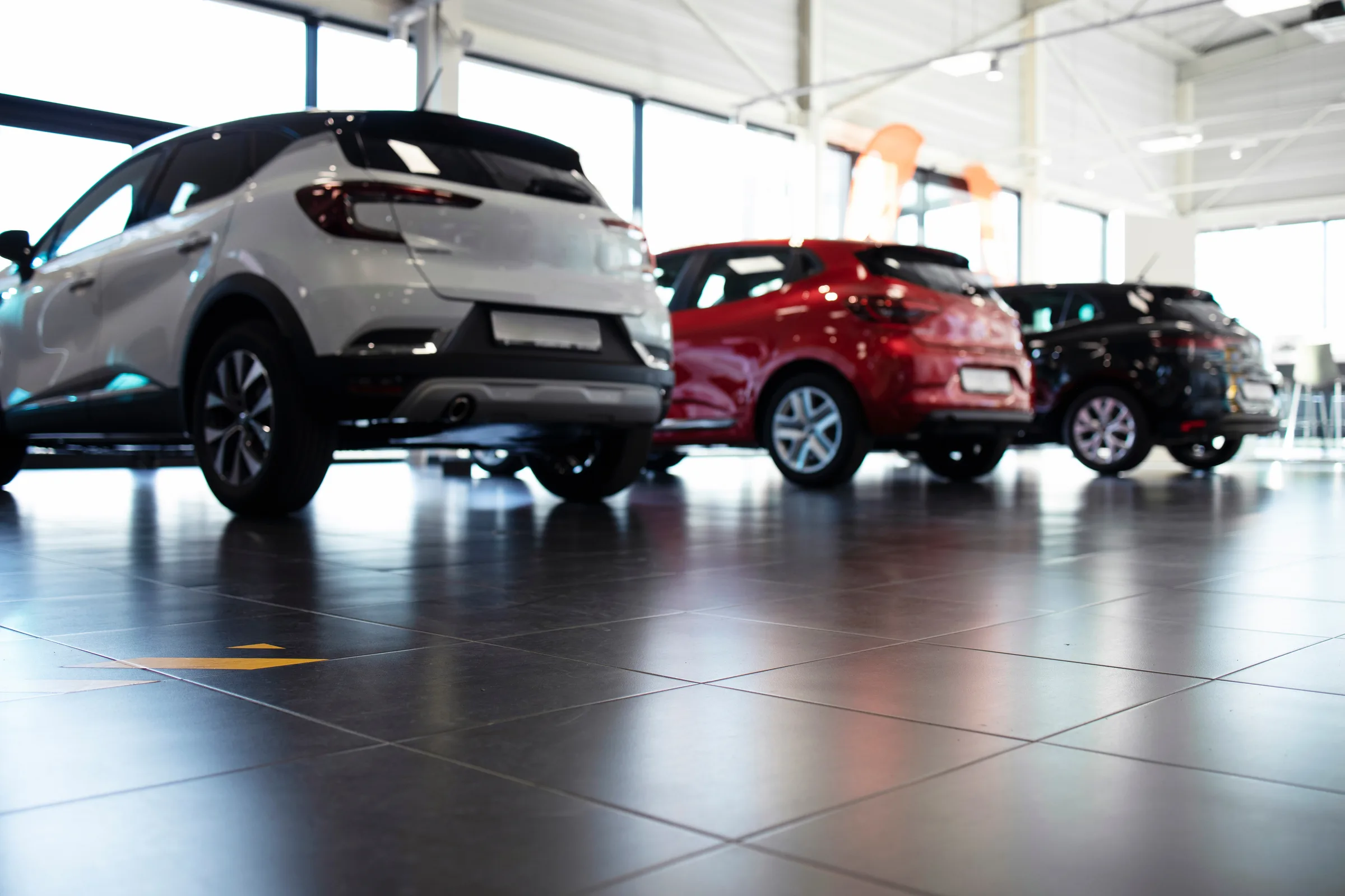 Row of new cars parked inside a bright dealership showroom